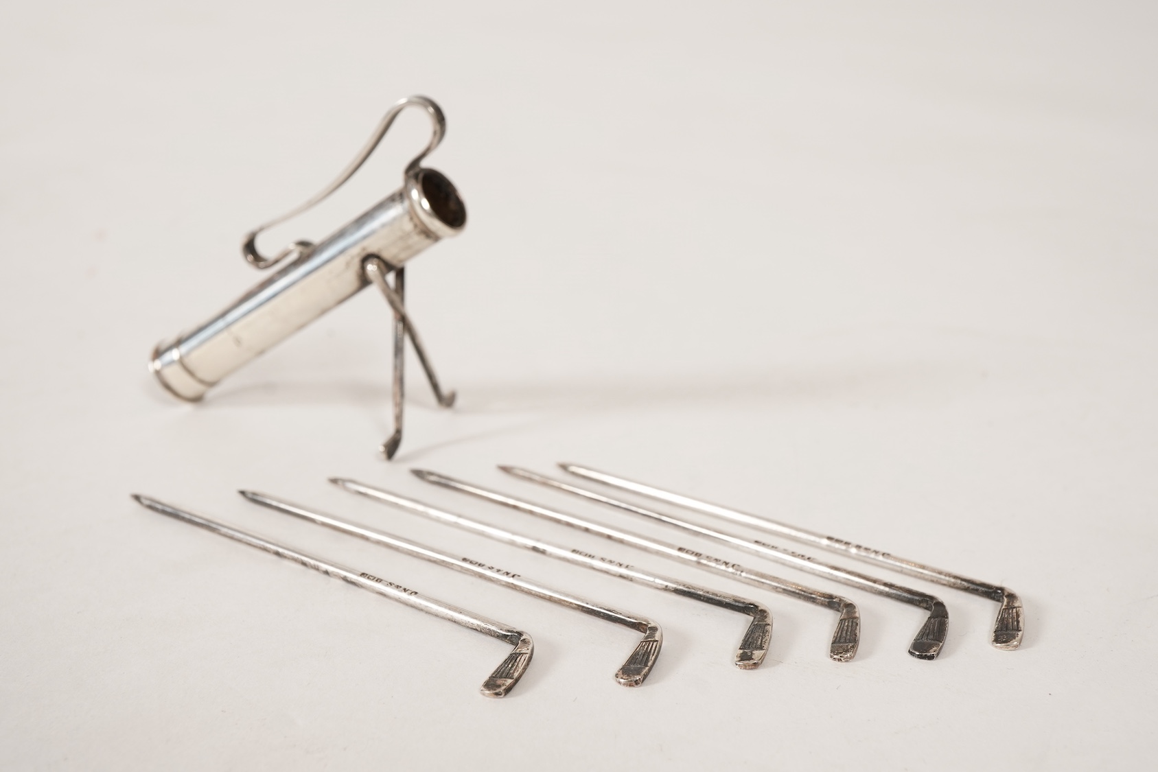 A set of six George V novelty silver cocktail sticks with holder, modelled as a golf bag with clubs, by John Nowill & Sons